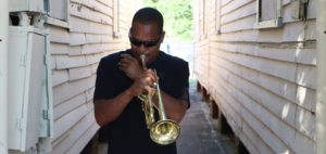 Derrick Shezbie, trumpeter of Rebirth Brass Band, practicing his trumpet on the side of Buddy Bolden's house.